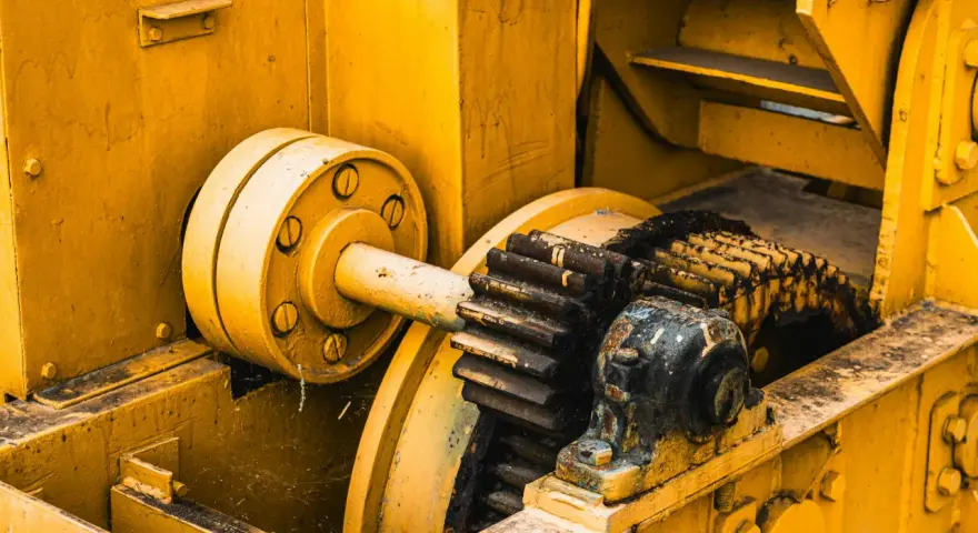 Żółta maszyna z zębatkami, gdzie różne rodzaje smarów chronią mechanizm przed zużyciem.
