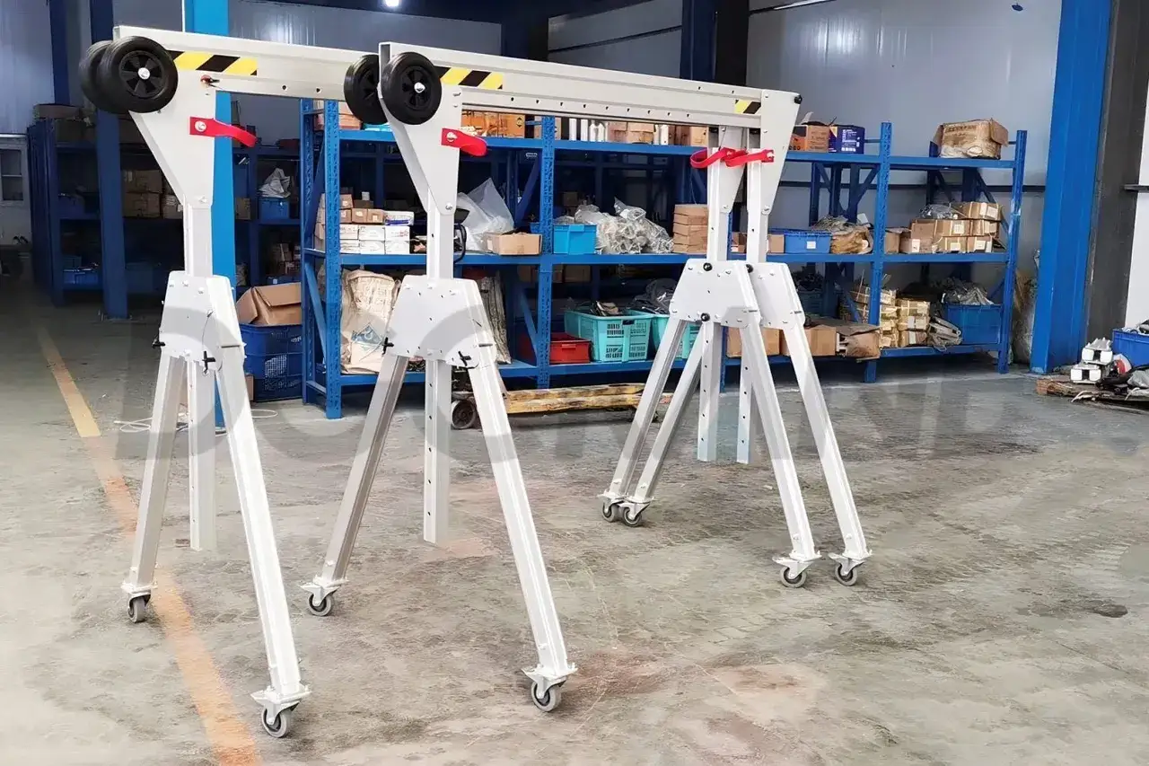 Dwa mobilne suwnice gantry crane stoją w magazynie, gotowe do pracy.