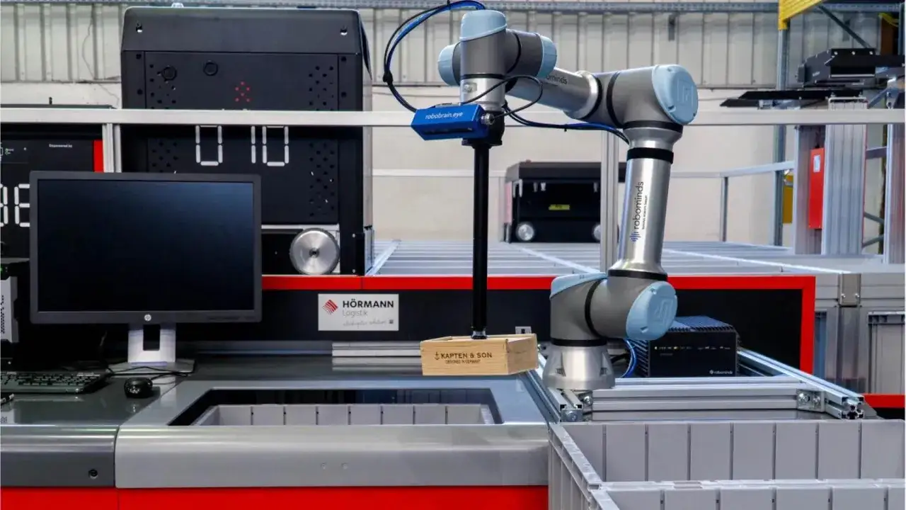 Robot chwyta drewniane pudełko w magazynie. System WMS steruje jego ruchem, usprawniając procesy logistyczne.