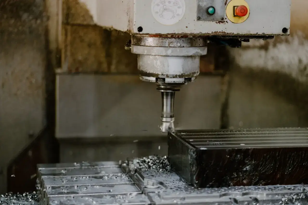 Precyzyjna obróbka CNC metalowego bloku. Wióry metalowe sypią się spod frezu, tworząc obraz precyzji i mocy.